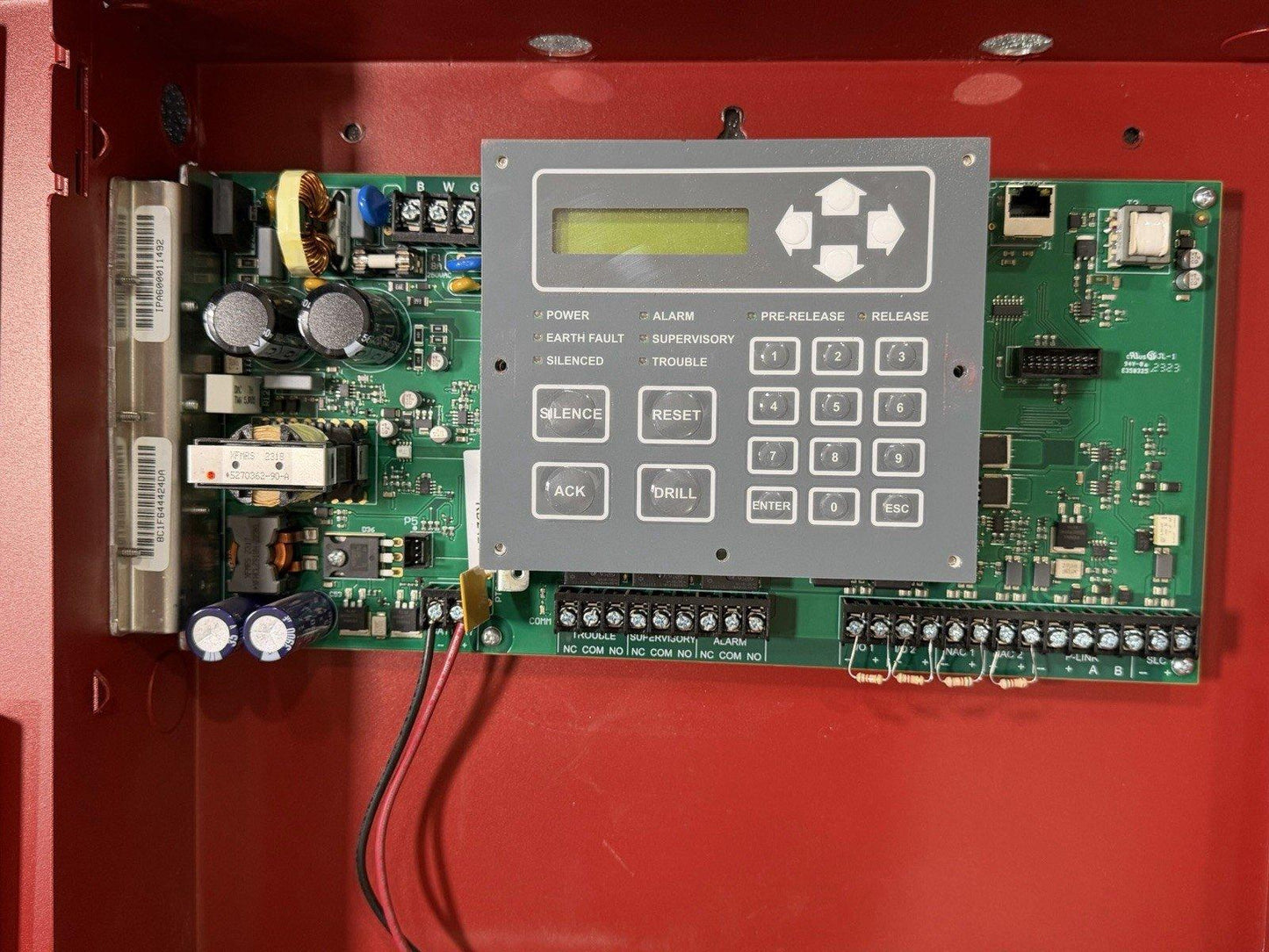 Fire alarm control panel with keypad, LCD display, and circuit board inside red enclosure