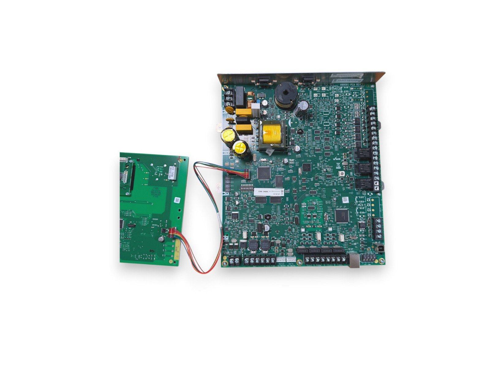 Fire alarm control panel circuit board with connected module and wiring, green PCB components visible