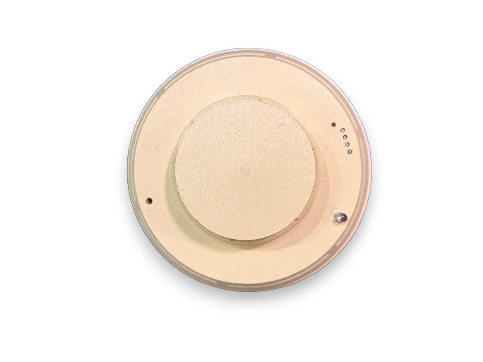 Beige ceiling-mounted fire alarm detector with sensor holes and mounting points