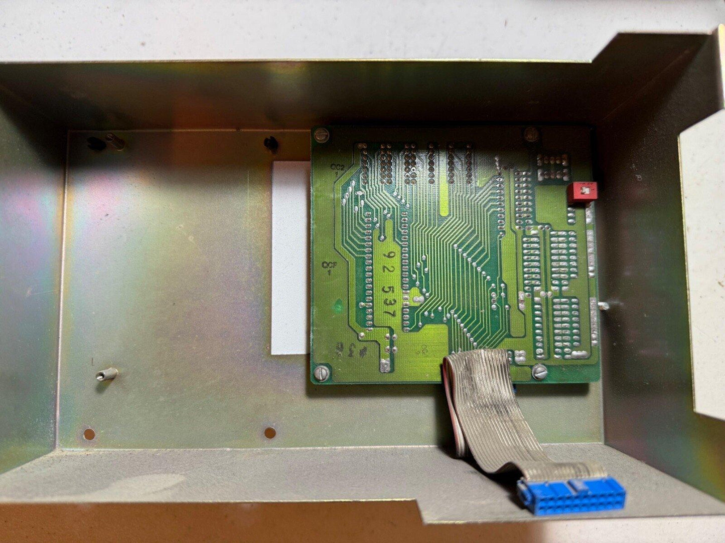 Fire alarm control panel circuit board with ribbon cable and blue connector inside metal enclosure