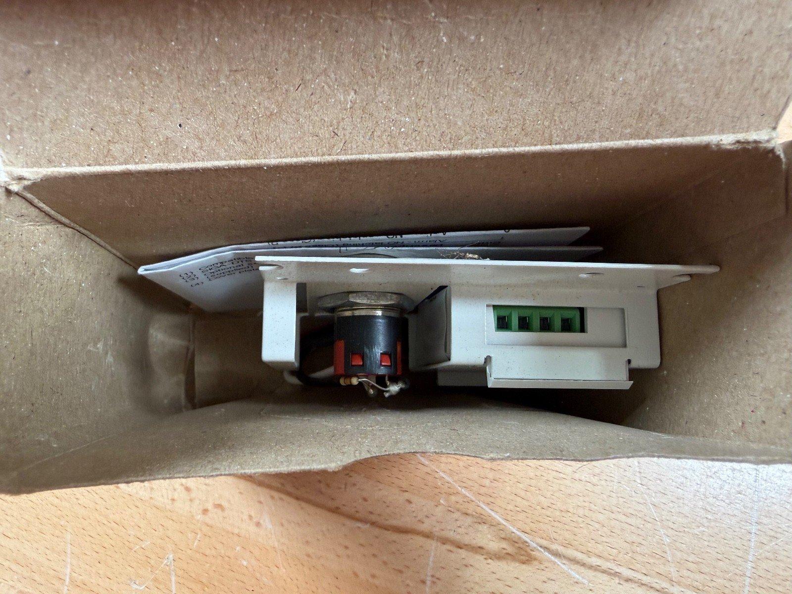 Fire alarm pull station with green terminal block inside cardboard box, used fire safety equipment