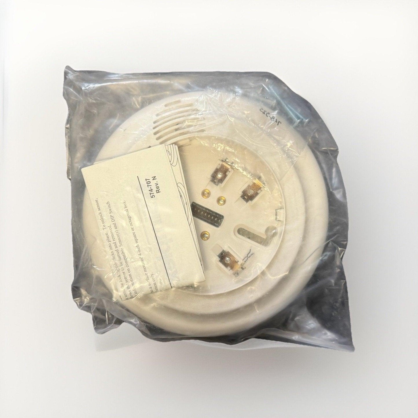 White fire alarm sensor in plastic wrap with instruction card, model 574-707, for commercial or residential use.