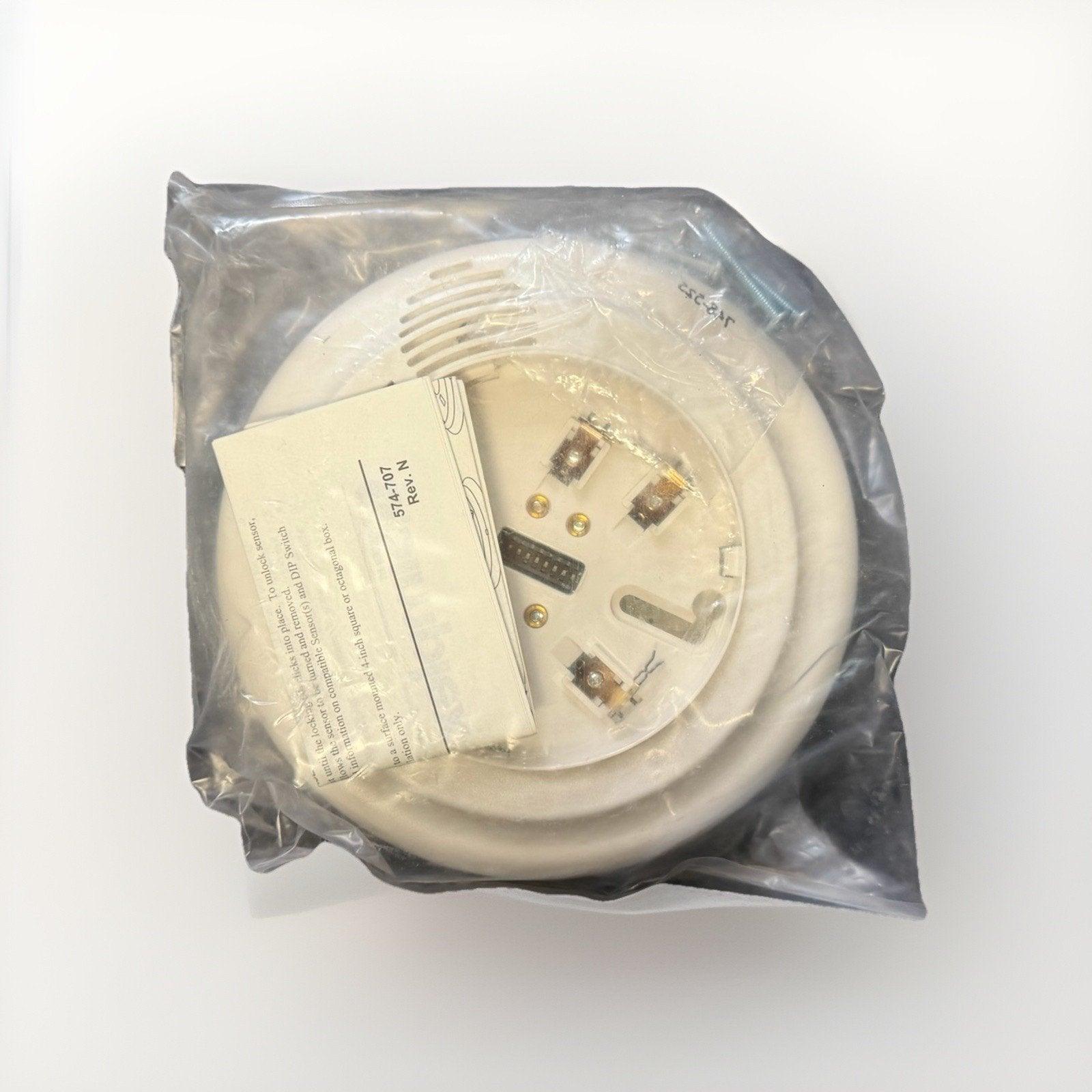 White fire alarm sensor in plastic wrap with instruction card, model 574-707, for commercial or residential use.