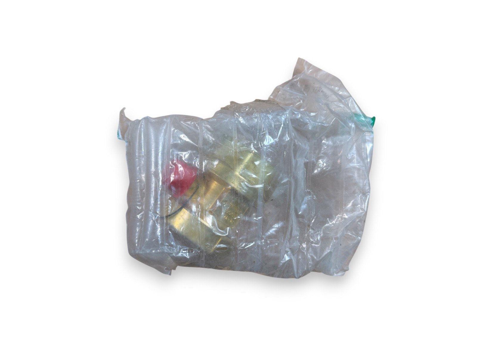 Fire alarm component in plastic wrap, gold body with red cap, surplus equipment