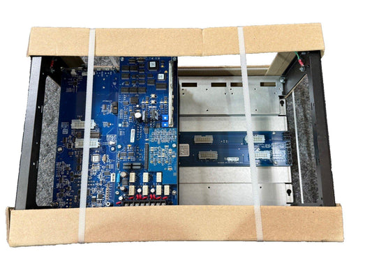 Fire alarm control panel with blue circuit boards, secured in cardboard packaging for shipping.