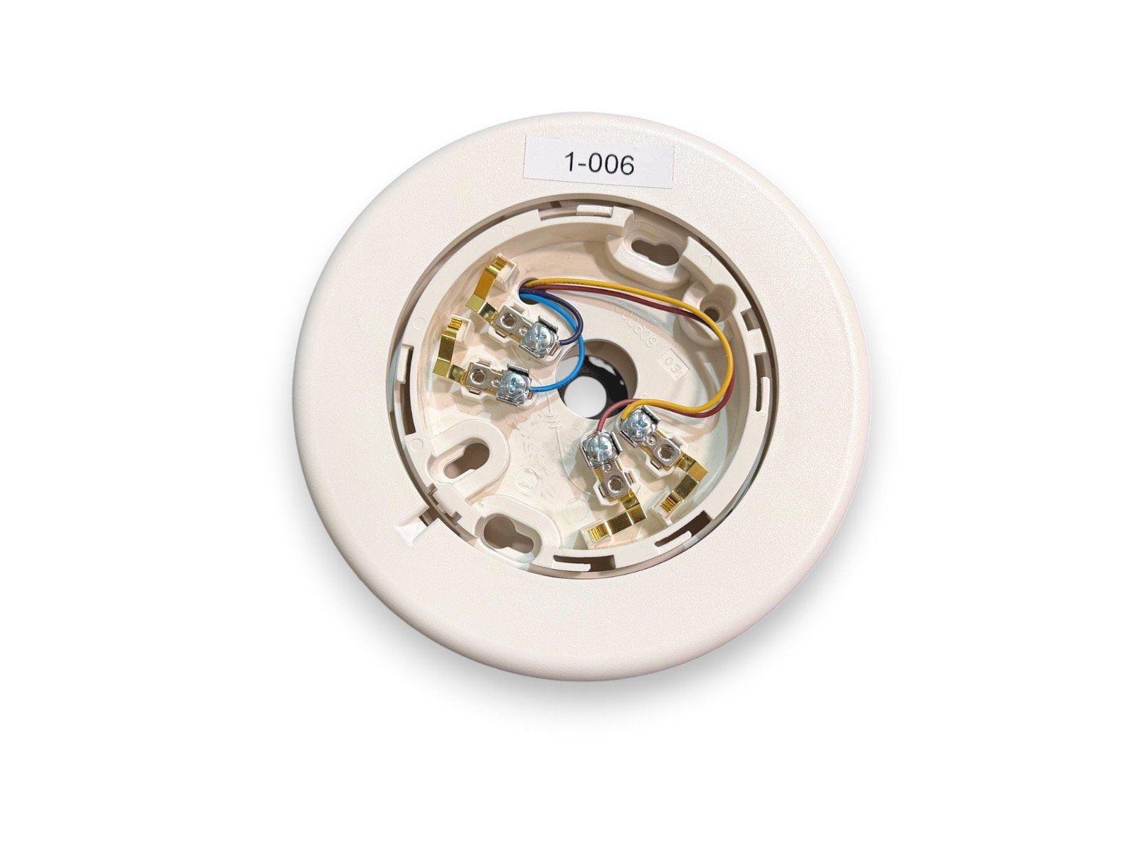 White fire alarm base with wiring terminals and label 1-006, for smoke detector installation