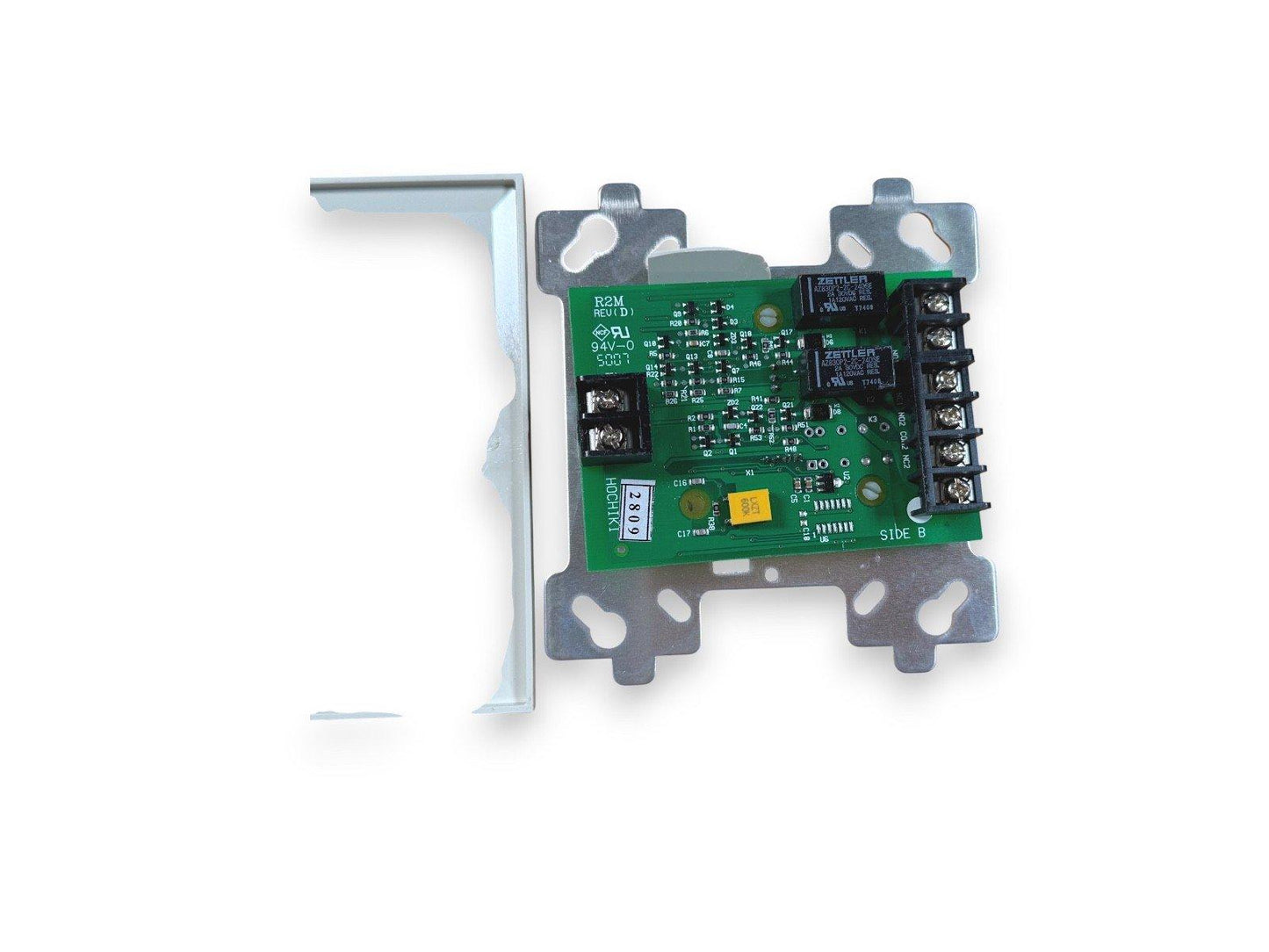 Fire alarm control module with green circuit board, terminal blocks, and metal mounting bracket