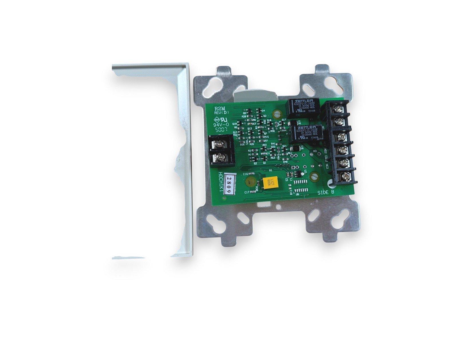 Fire alarm control module with green circuit board, terminal blocks, and metal mounting bracket