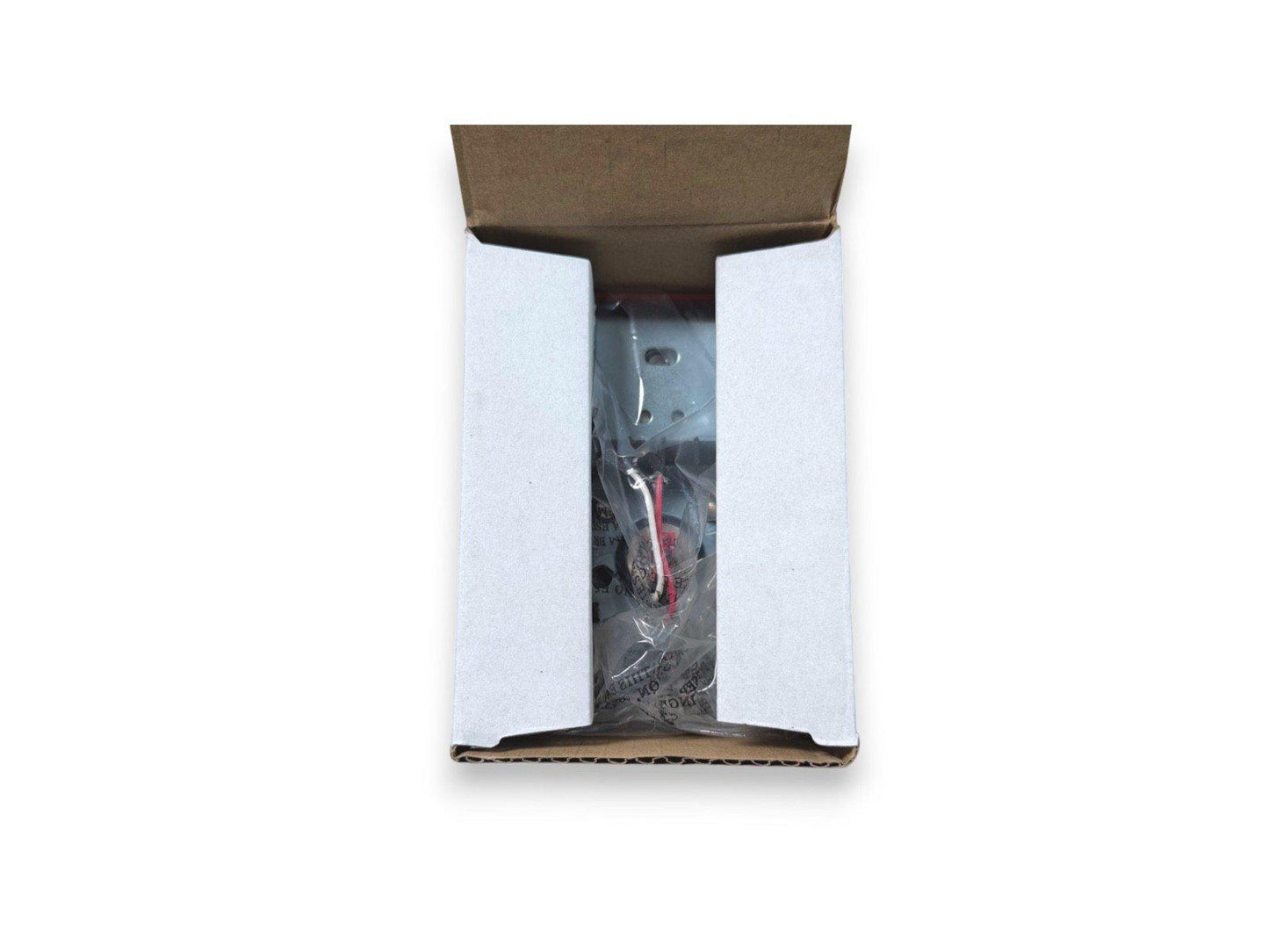 Fire alarm component in open box with protective packaging and wiring visible