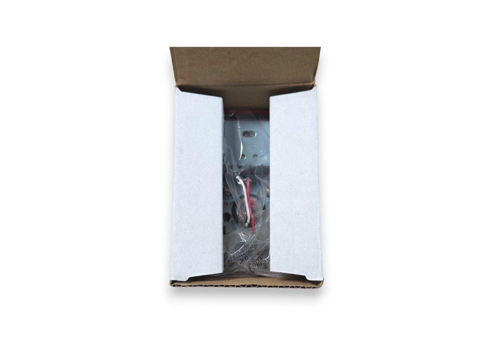 Fire alarm component in open box with protective packaging and wiring visible