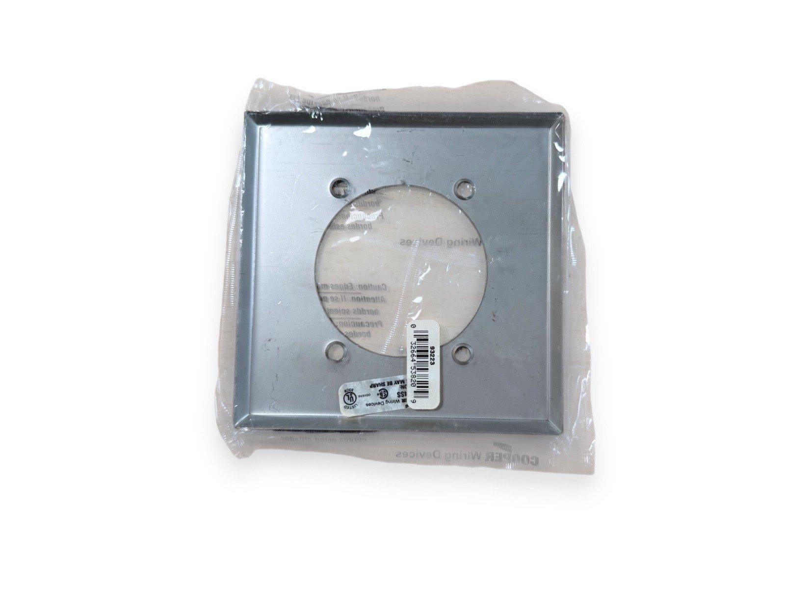Square metal fire alarm mounting bracket with circular cutout, packaged in plastic wrap