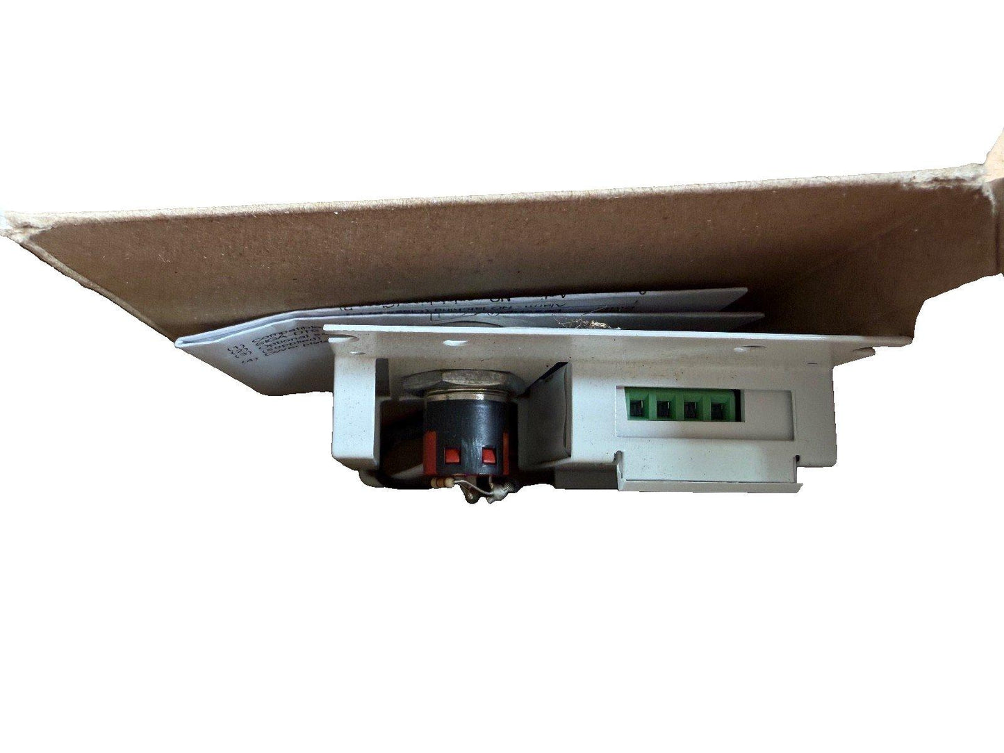 Fire alarm device with green terminal block and wiring, shown under cardboard packaging