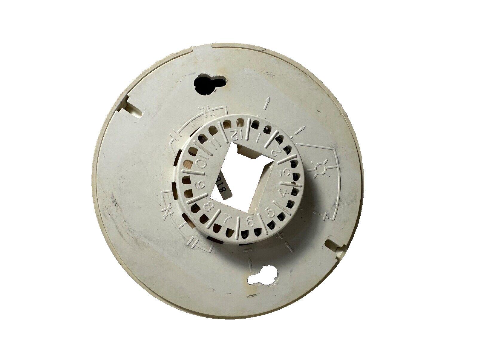 White fire alarm base with numbered terminals and mounting slots for security systems