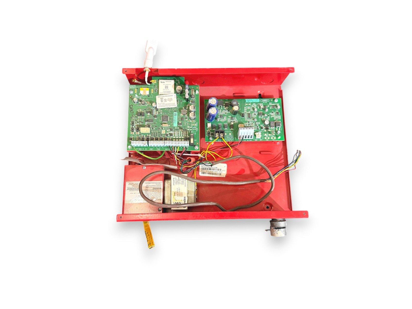 Red fire alarm control panel with exposed circuit boards and wiring for commercial fire safety systems