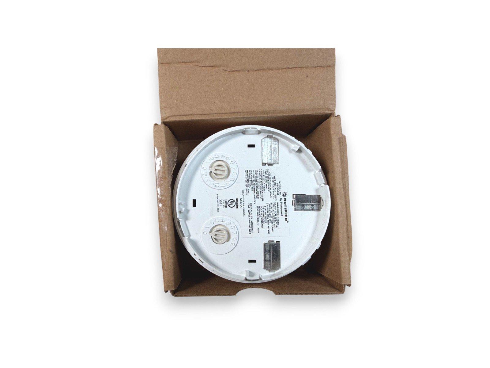 Notifier fire alarm control module in open box, white circular device with wiring terminals and labels