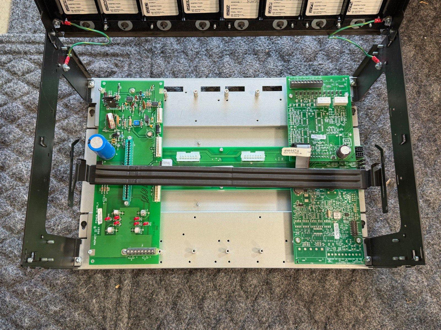 Fire alarm control panel with green circuit boards and wiring, showing internal components for fire safety systems.