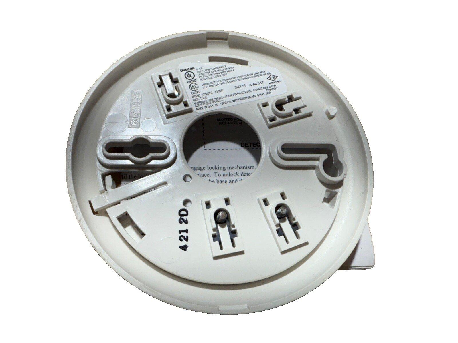 White fire alarm base with UL listed label and mounting slots for smoke detector installation
