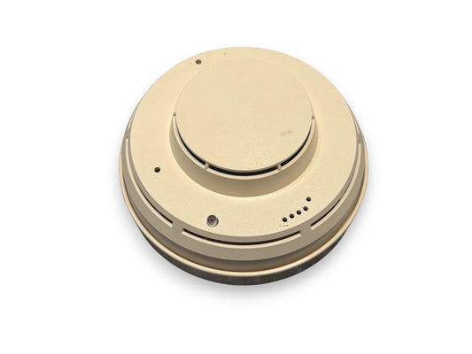 Beige fire alarm detector with circular design and mounting holes, ideal for home or commercial safety systems.