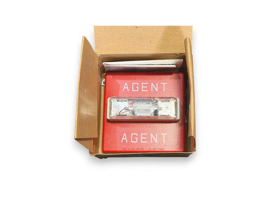 Red AGENT fire alarm device in open box with clear lens, labeled 'FIRE ALARM DEVICE - DO NOT PAINT'