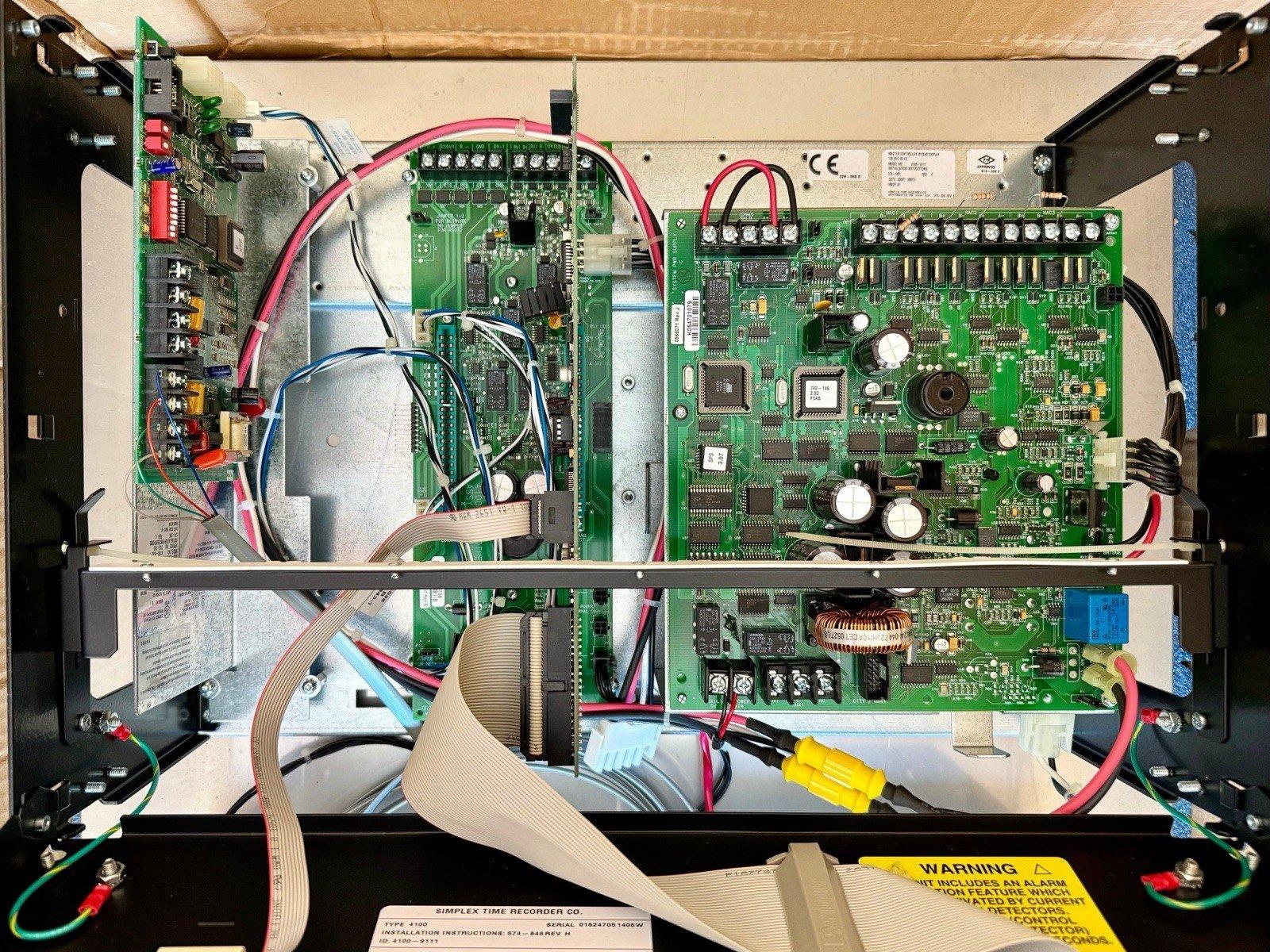 Fire alarm control panel interior with circuit boards, wiring, and connectors for commercial security systems