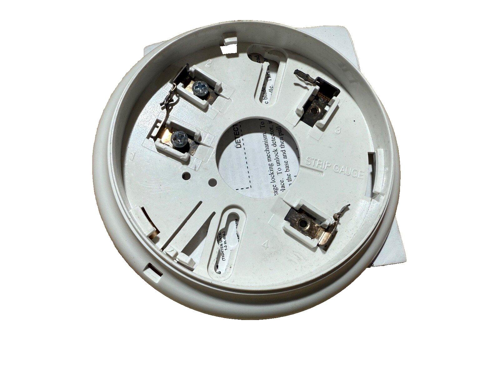 White fire alarm base with wiring terminals and strip gauge for smoke detector installation