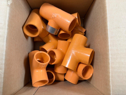 Orange PVC fire alarm conduit fittings in cardboard box, compatible with fire safety systems