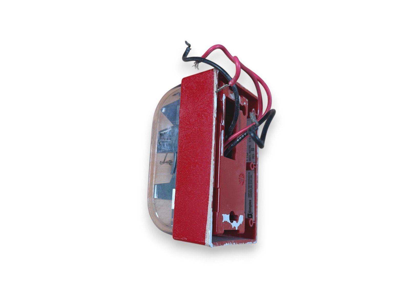 Red fire alarm strobe with exposed wiring and clear lens, used fire safety equipment