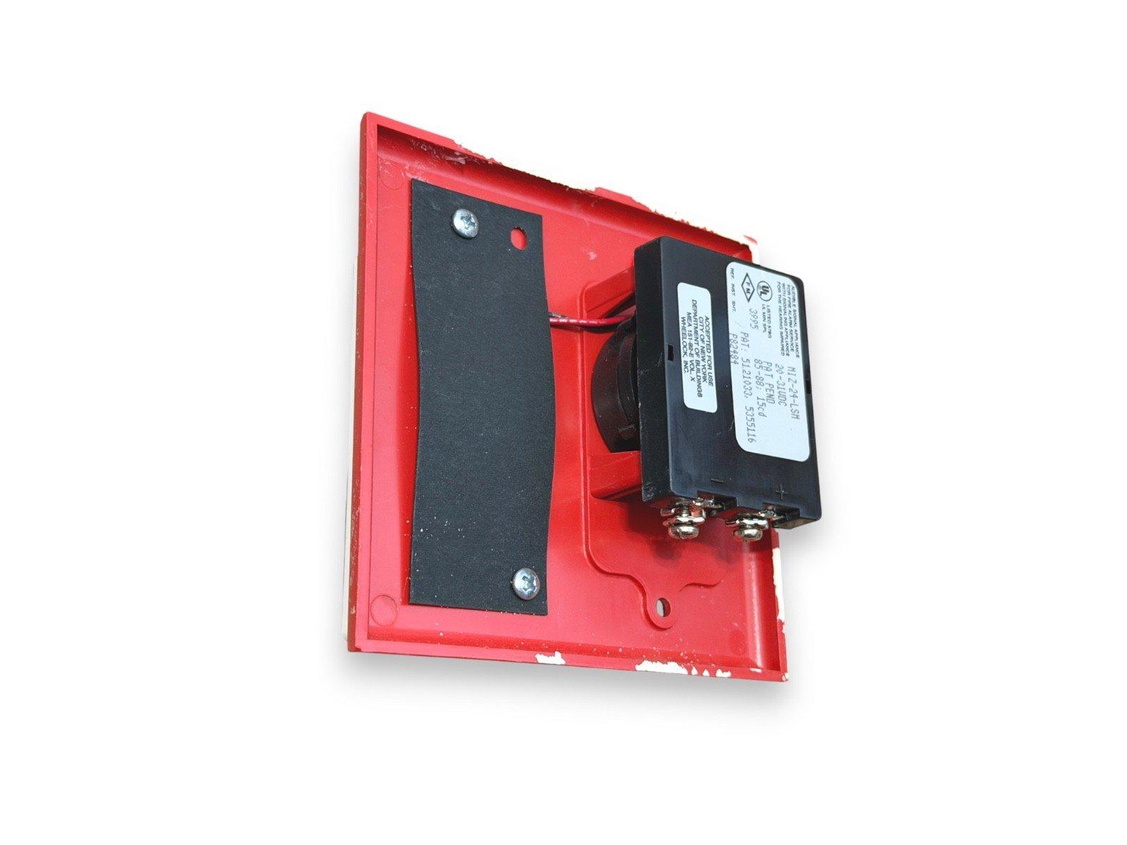 Red fire alarm sounder with black speaker and wiring terminals, used fire safety equipment