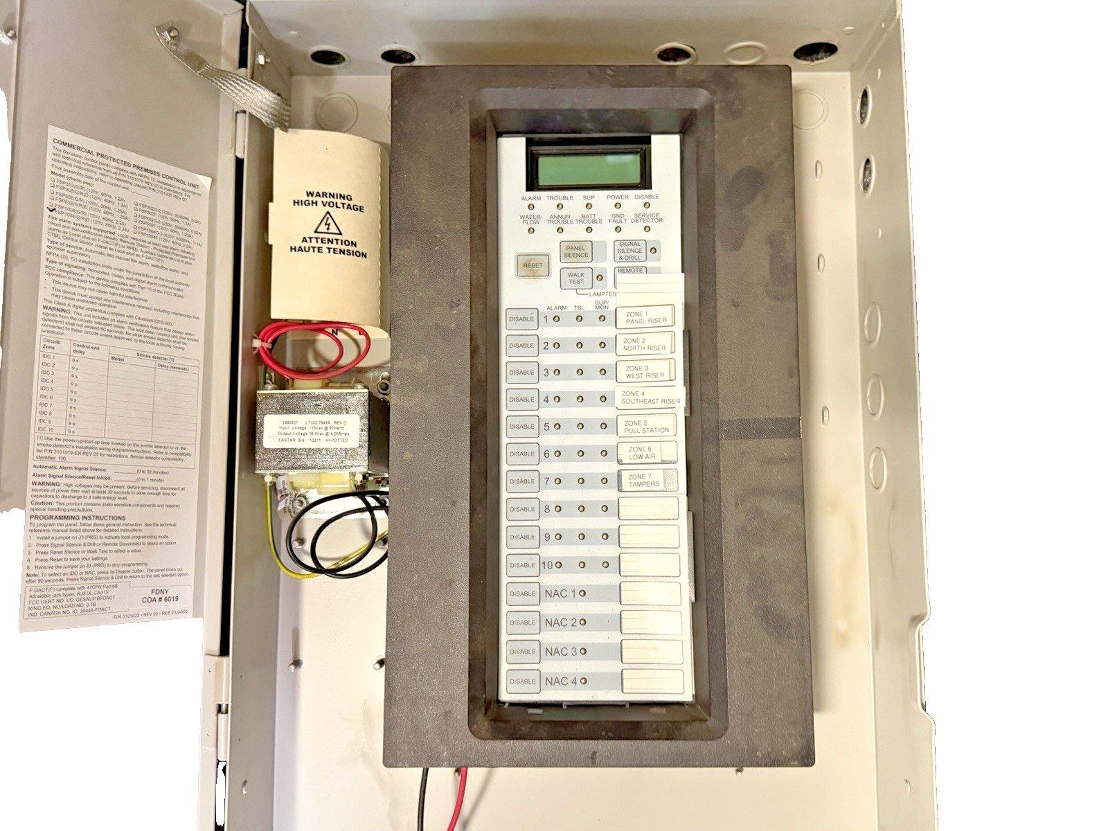 Fire alarm control panel with digital display, zone buttons, and wiring, for commercial fire safety systems.